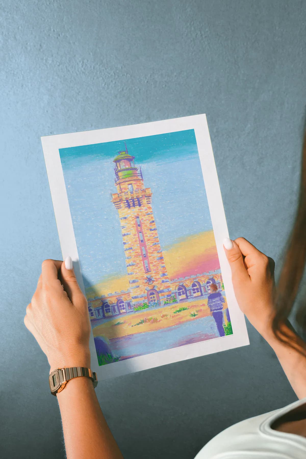 Le print Phare tenu à deux mains devant un mur bleu.